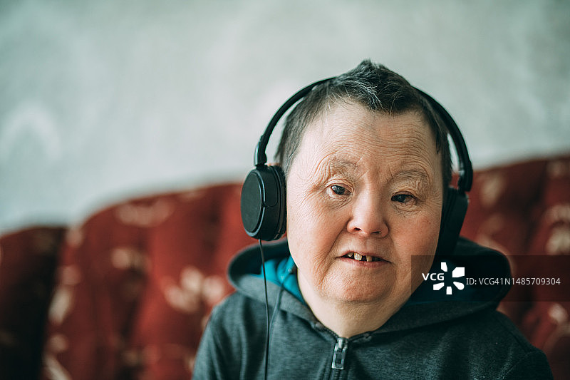 患有唐氏综合征戴着耳机听音乐的老年妇女图片素材