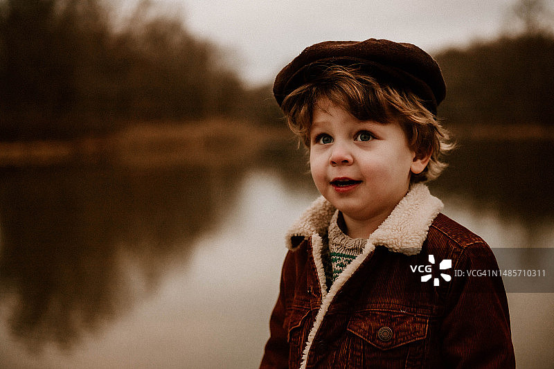 戴报童帽的男孩在池塘前图片素材