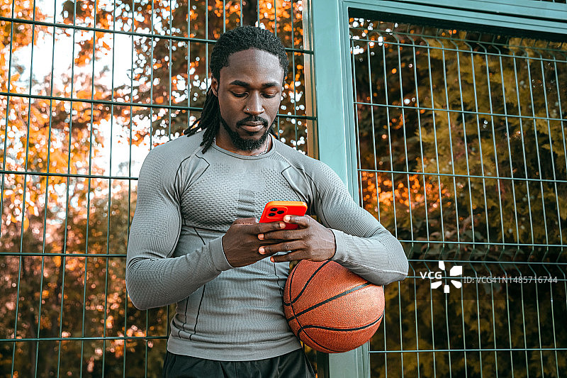 现代篮球运动员使用手机体育App图片素材
