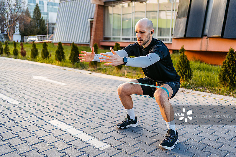 在公园使用阻力带锻炼的年轻男人图片素材