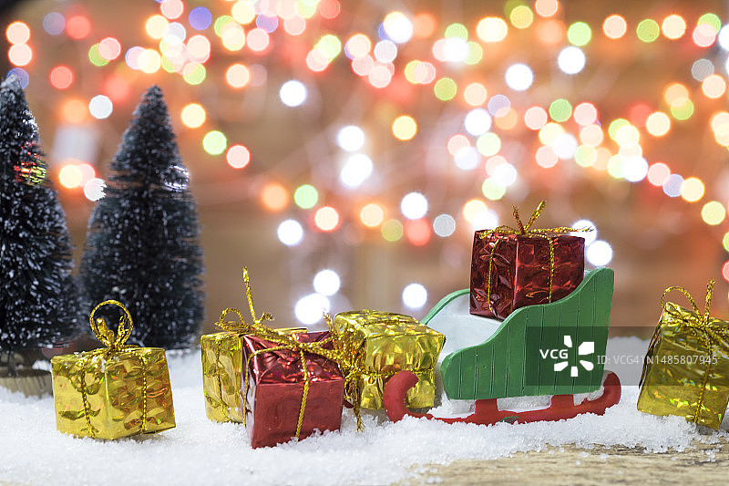 圣诞灯光背景上的雪橇和礼品盒图片素材