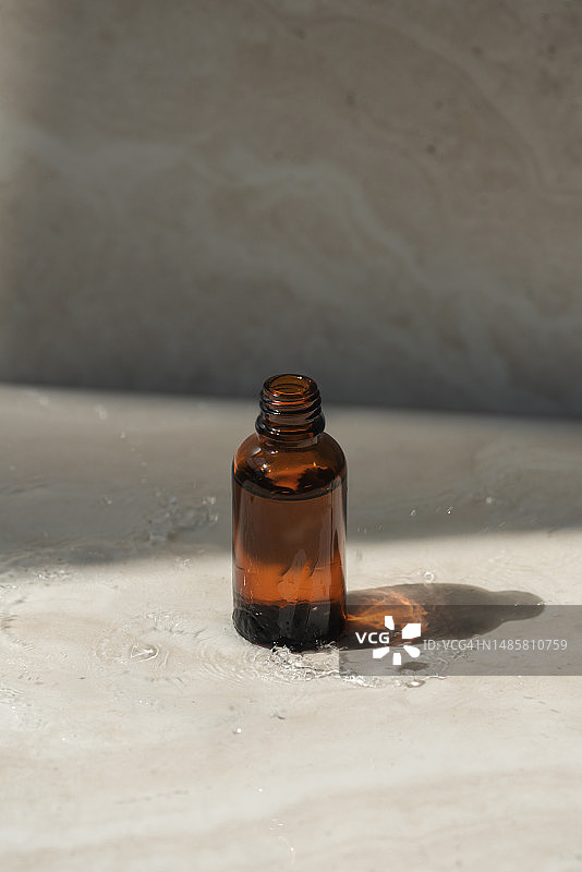 打开的琥珀色滴管瓶，大理石上的精华液或精油，生态化妆品包装概念图片素材