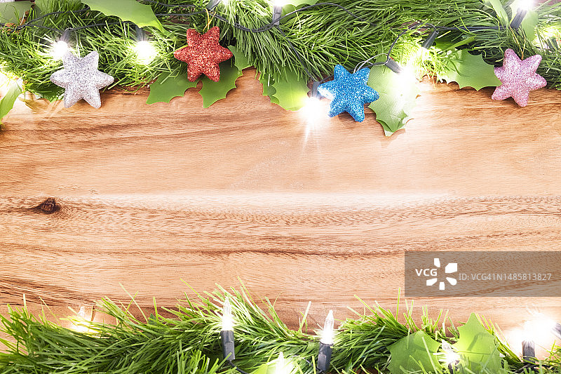 圣诞背景：木桌上的绿色树叶和圣诞装饰品图片素材