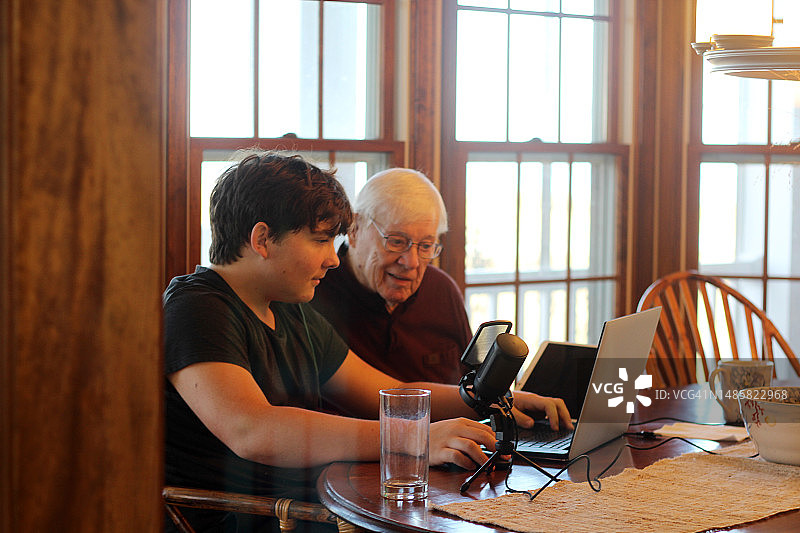 周末家庭出游：少年与祖父在笔记本电脑上工作图片素材