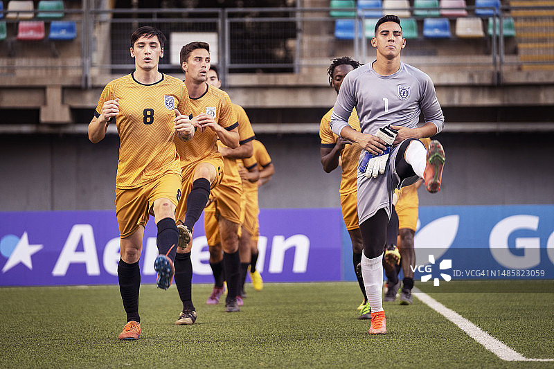 专注的男足球运动员有组织地站在运动场上热身图片素材