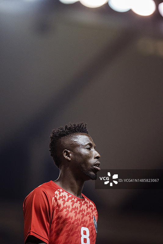 在泛光灯下体育场内，健壮的职业足球运动员的侧面轮廓画像图片素材