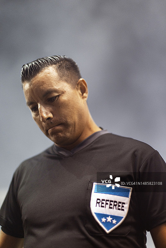 足球比赛开始前，成年男性专业裁判站在戏剧性的雾背景中的场地上图片素材