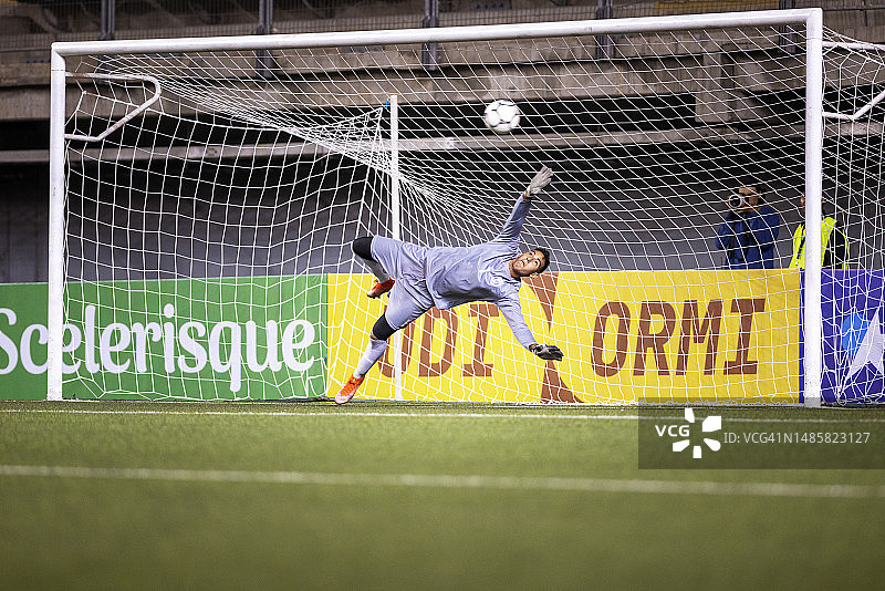 职业男性守门员在足球锦标赛中跃起试图挡球图片素材