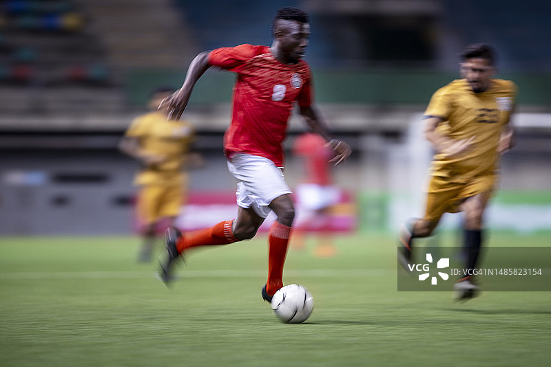 职业足球运动员在体育场上踢球的模糊瞬间图片素材