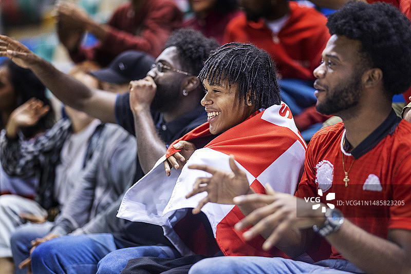 运动迷坐在体育场看台上，热情地为他们最喜欢的球队在足球比赛中加油图片素材