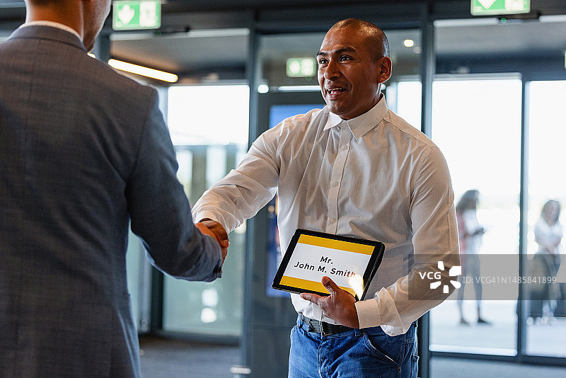 拉丁裔男司机与抵达机场的客户握手图片素材