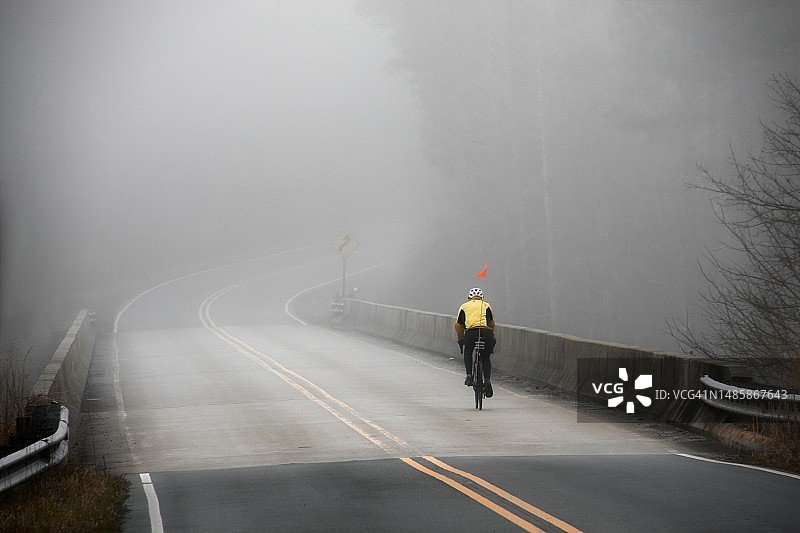 在雾蒙蒙的乡村公路桥上的剪影骑自行车者图片素材