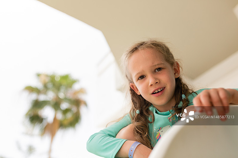 夏天，坐在酒店阳台上的小女孩图片素材