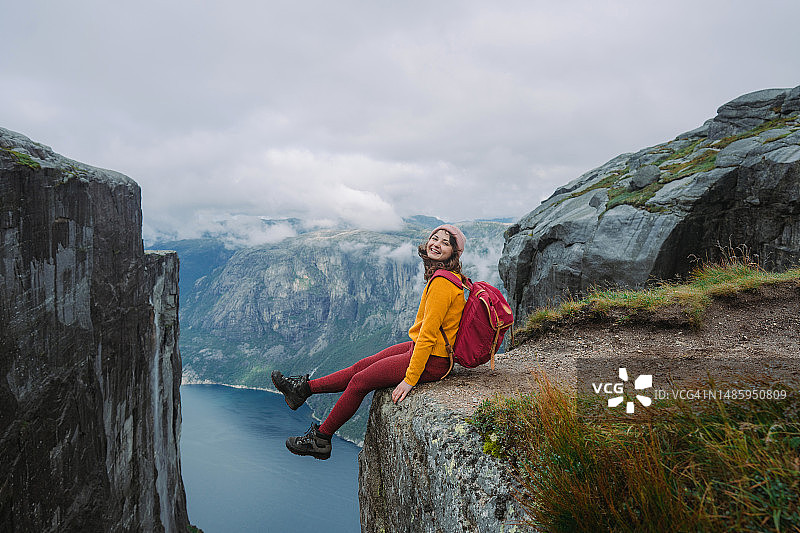 女人坐在吕瑟峡湾上方的悬崖上图片素材
