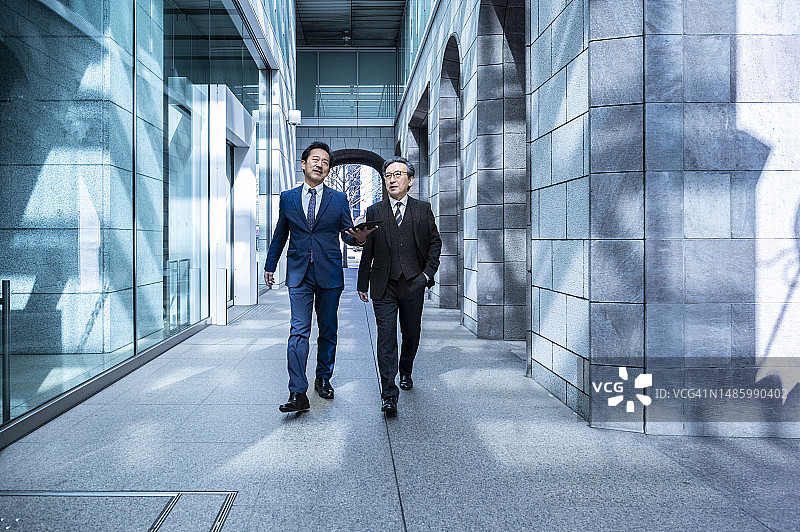 两位商人在金融区手持平板电脑行走图片素材