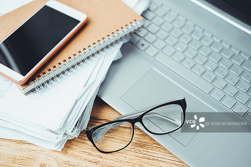 智能手机、笔记本、纸张和眼镜在打开的笔记本电脑上图片素材