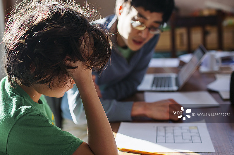 孩子在家从父亲那里获得家庭作业帮助的背影图片素材