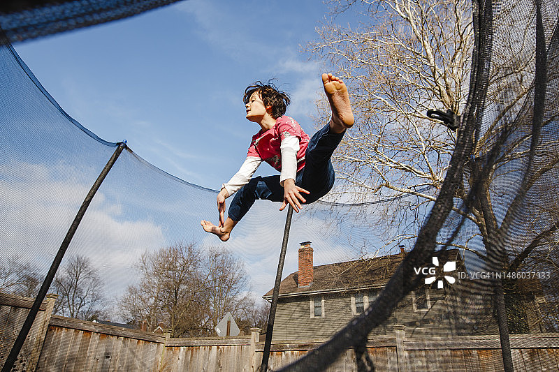 快乐的男孩在户外蹦床上跳跃图片素材