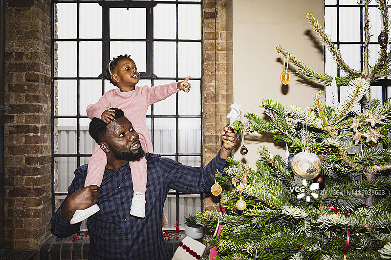 父亲和年幼的女儿欣赏圣诞树装饰品图片素材