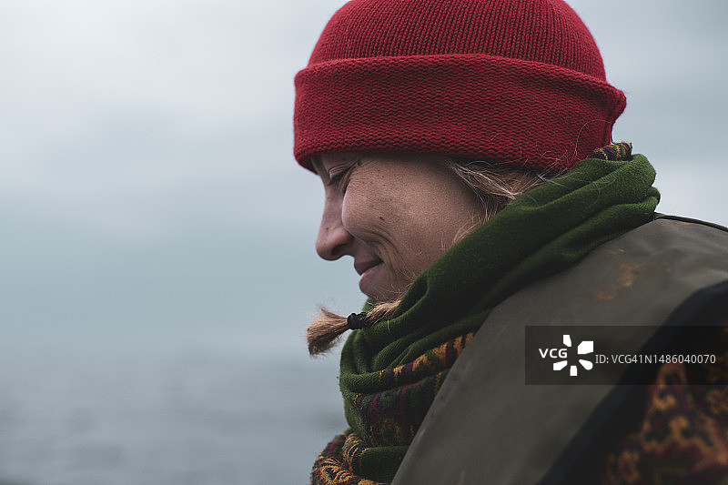 在苏格兰的船上，戴着红色无檐小便帽微笑的女人图片素材