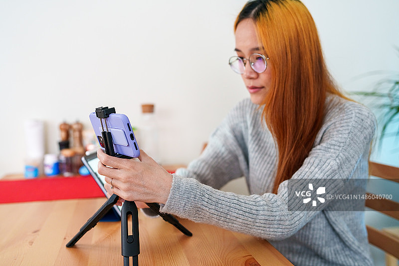 用三脚架和手机拍摄视频的女人图片素材