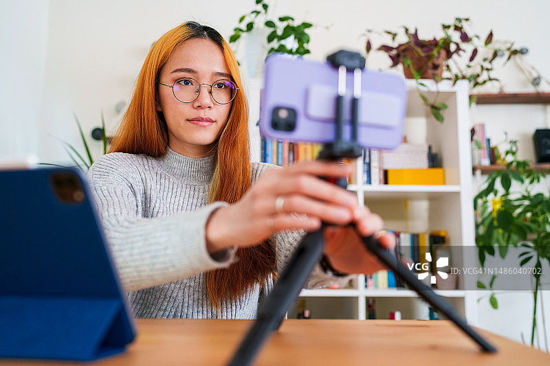 用三脚架和手机拍摄视频的女人图片素材