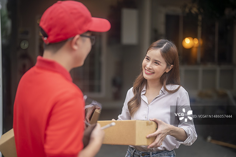 配送概念：亚洲男人在家接收送货员的快递箱图片素材