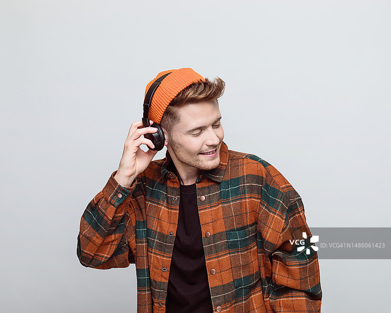 戴着无檐小便帽和耳机的年轻男子的肖像图片素材