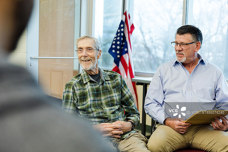 男理疗师观察老年男性与小组成员互动图片素材