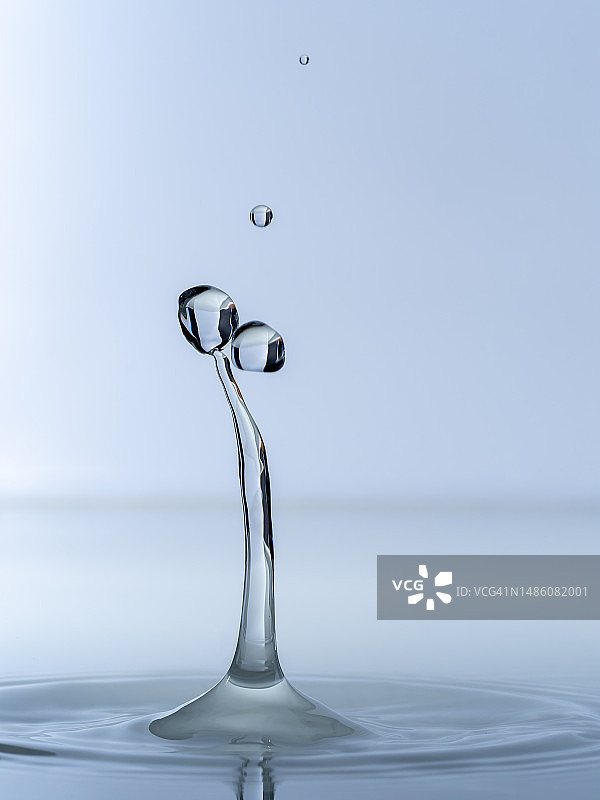 水滴滴落并飞溅在蓝色背景的水面上图片素材