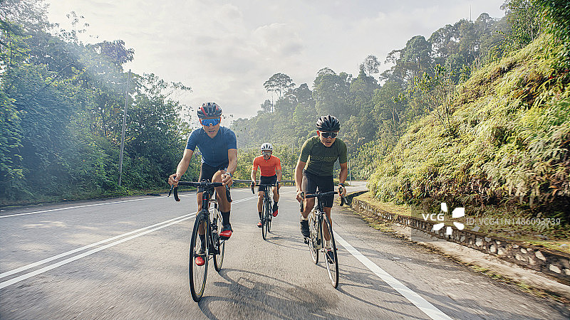 亚洲华人男子在乡村骑自行车下坡图片素材