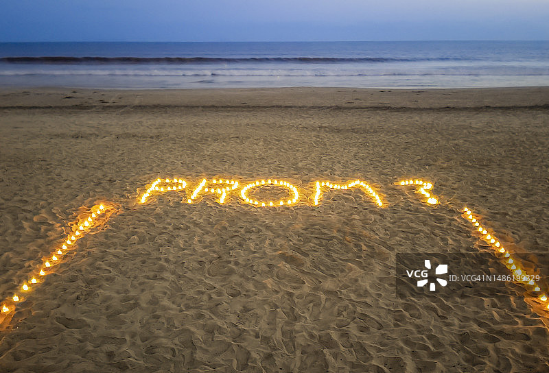 海滩上用蜡烛拼出的舞会邀请图片素材