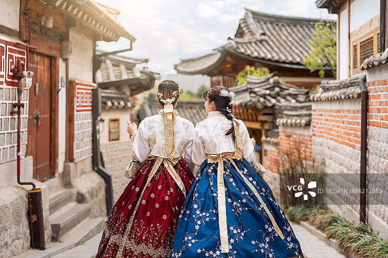 两名穿着韩服的女子走在首尔北村韩屋村传统住宅中的背影图片素材
