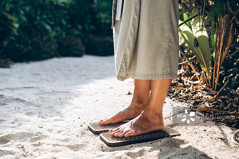 赤脚站在靠近苦行僧的沙滩上的女人图片素材