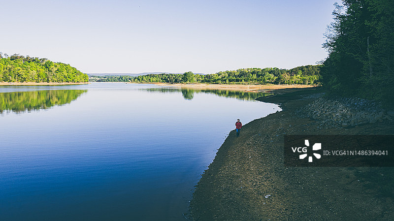 红夹克女子在湖边徒步的航拍视角图片素材