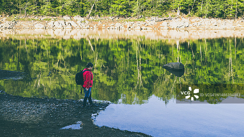 红夹克女子在湖边徒步的航拍视角图片素材