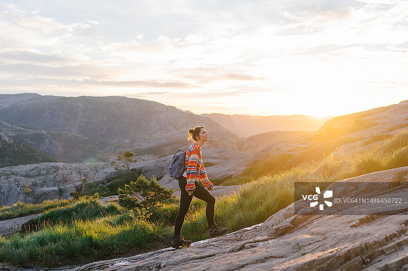 日出时分在挪威徒步前往圣坛岩的女人图片素材