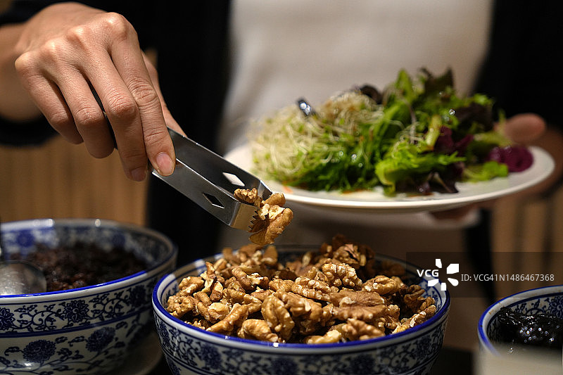 女人在沙拉吧用夹子夹核桃特写图片素材
