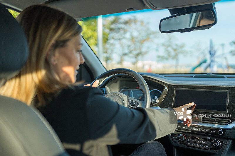 白人女性开车并操作触摸屏图片素材