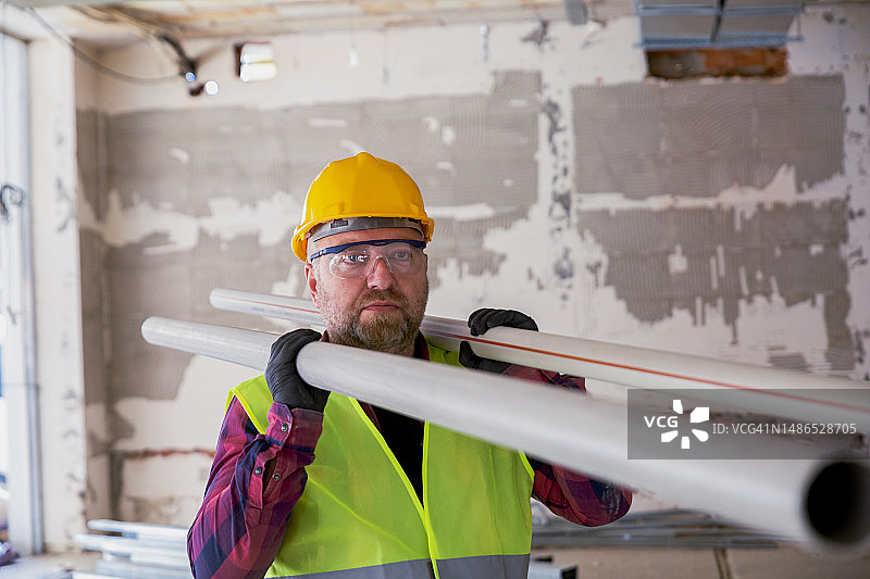建筑工人搬运两根管子到施工现场图片素材