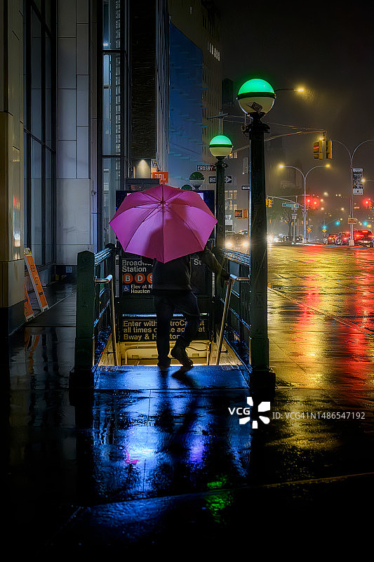 在纽约休斯顿街地铁站打着粉色雨伞的男人图片素材