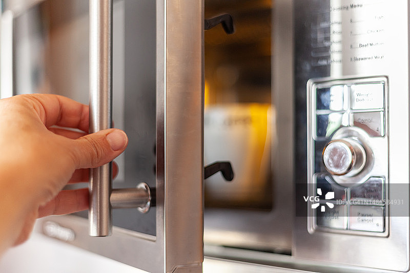 女人使用微波炉。在微波炉中加热饮料图片素材