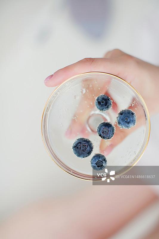 手持蓝莓香槟酒杯的女人图片素材