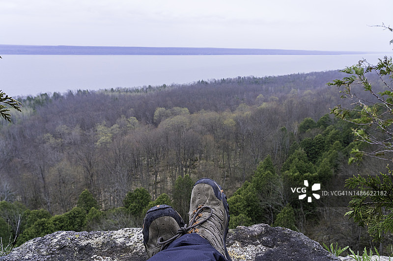 成年男性徒步旅行者站在悬崖边俯瞰湖面图片素材