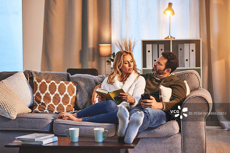 爱：情侣在沙发上放松交谈，享受宁静夜晚图片素材