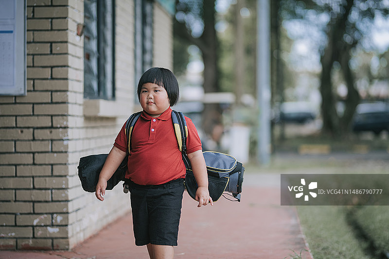 中国小男孩带着高尔夫球包去高尔夫球练习场上课图片素材