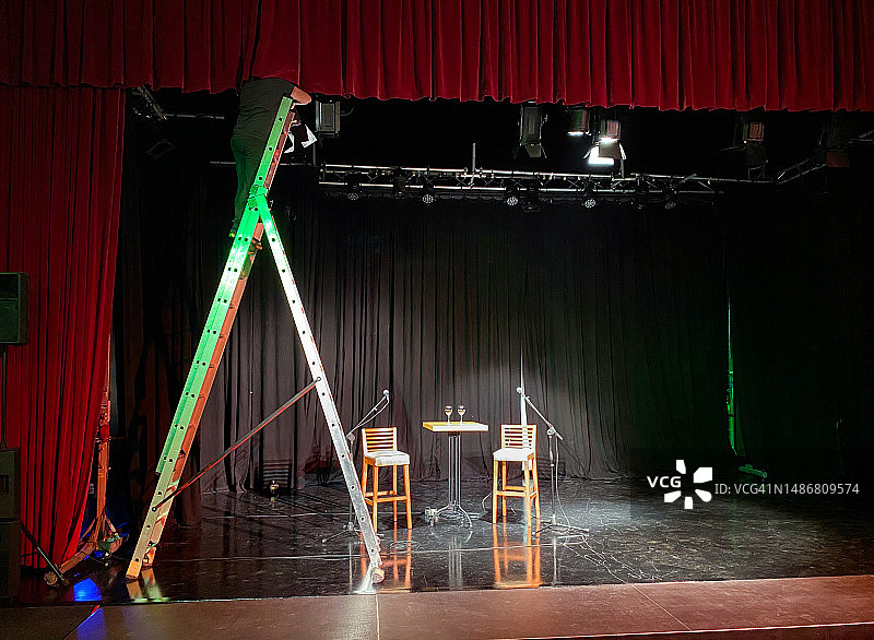 年轻的灯光技术员站在梯子上安装聚光灯图片素材