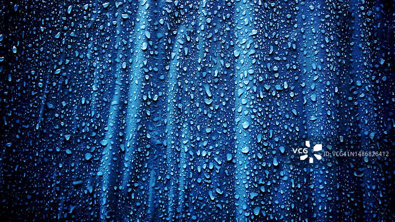 光影之间：美国纽约曼哈顿墙壁上蓝色海报的雨滴特写图片素材