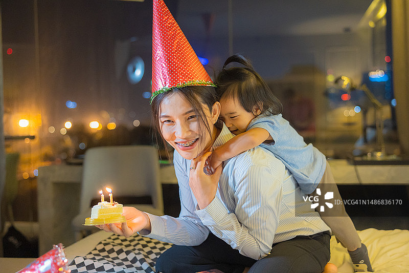 快乐的亚洲母亲在卧室里为小女儿布置生日派对图片素材