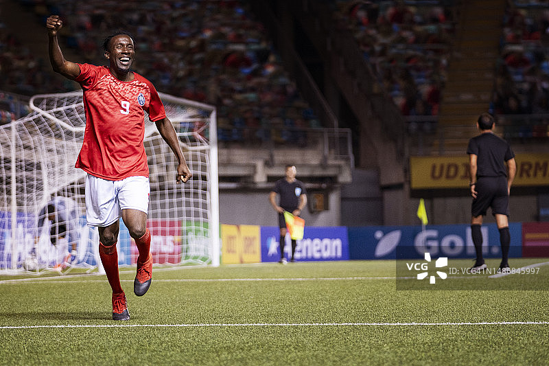 兴奋的男足球运动员举起手臂，挥舞着庆祝的拳头图片素材